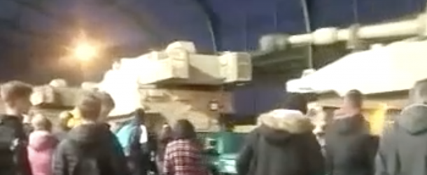 Screenshot from a Telegram video showing US M109 Paladin artillery systems on a westward train passing through a train station platform in Legnica, Poland. Text that accompanied the video inaccurately claimed the train was heading east.