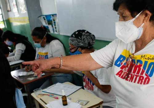 A health worker gestures during a day of immunization against Covid-19 with the compound manufactured in China Sinopharm aimed at high school students at a high school in the west of the city, in Caracas, Venezuela, October 29, 2021.