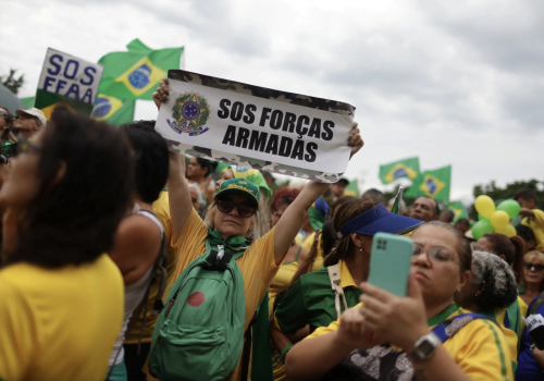 People gather during a protest held by supporters of Brazil’s President Jair Bolsonaro at the Army headquarters in Rio de Janeiro, Brazil, November 15, 2022. The sign reads: “SOS Army Forces.” (Source: REUTERS/Pilar Olivares)