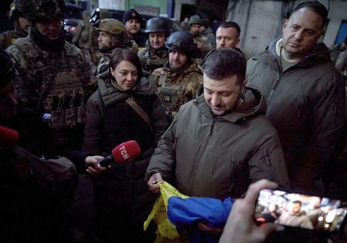 Ukrainian President Volodymyr Zelenskiy holds a national flag as he visits a position of Ukrainian service members in the frontline town of Bakhmut, Donetsk Oblast, December 20, 2022. (Source: Ukrainian Presidential Press Service/Handout via Reuters Connect)