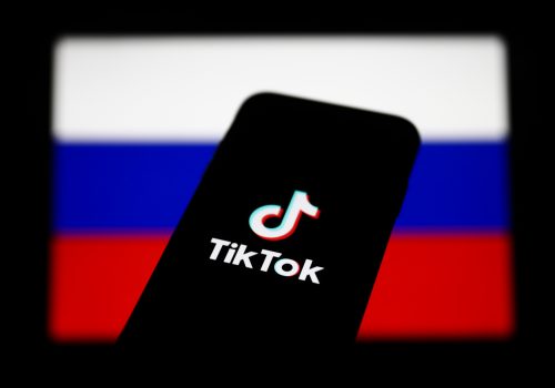 TikTok logo displayed on a phone screen and Russian flag displayed on a screen in the background are seen in this illustration photo taken in Krakow, Poland on March 1, 2022. (Photo Illustration by Jakub Porzycki/NurPhoto)