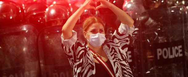 A demonstrator makes a heart-shaped gesture while standing in front of a police cordon during a rally to protest against the so-called foreign agents bill in Tbilisi, Georgia, May 1, 2024. (Source: REUTERS/Irakli Gedenidze/File Photo)
